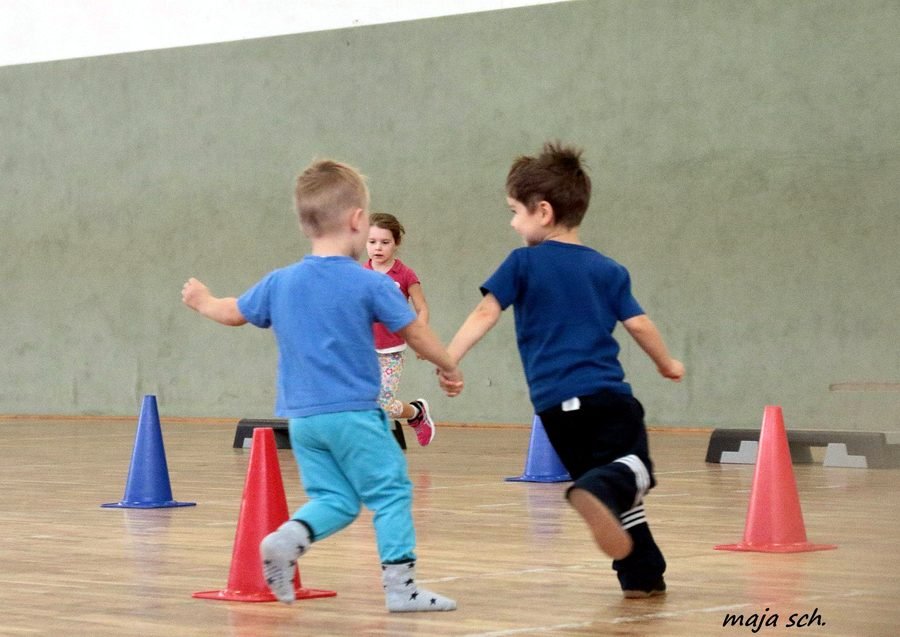 Zwei Jungen laufen zwischen bunten Hütchen durch die Halle.