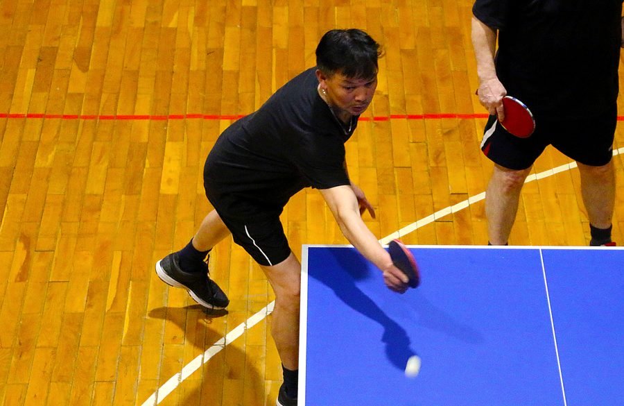 Spieler beim Aufschlag an der Tischtennisplatte.