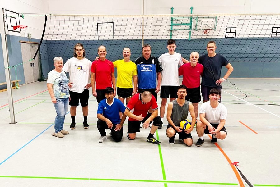 Gruppenbild der Volleyballmannschaft vor dem Netz.